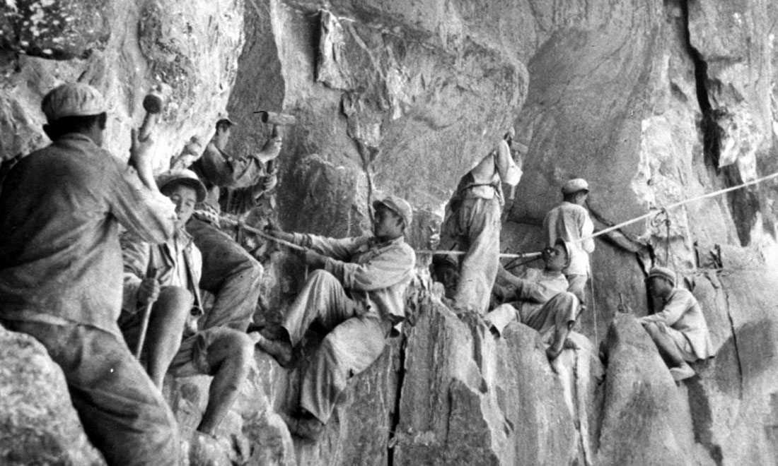 1954年，修筑康藏公路的解放軍戰(zhàn)士們在怒江兩岸的懸崖陡壁上辟山筑路。新華社稿 李萬春、張加里攝